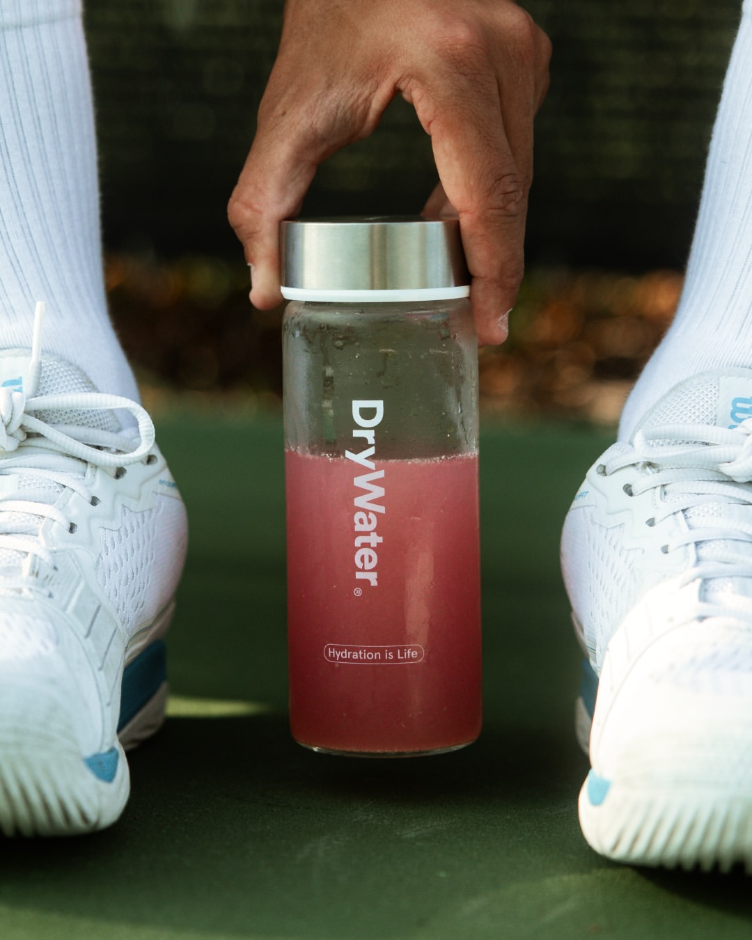 A DryWater bottle set down on court between a player's shoes
